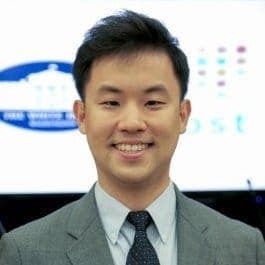 Hyunsoo Chang: An Asian Man in a gray suit and blue tie with the logo of the white house in his background.