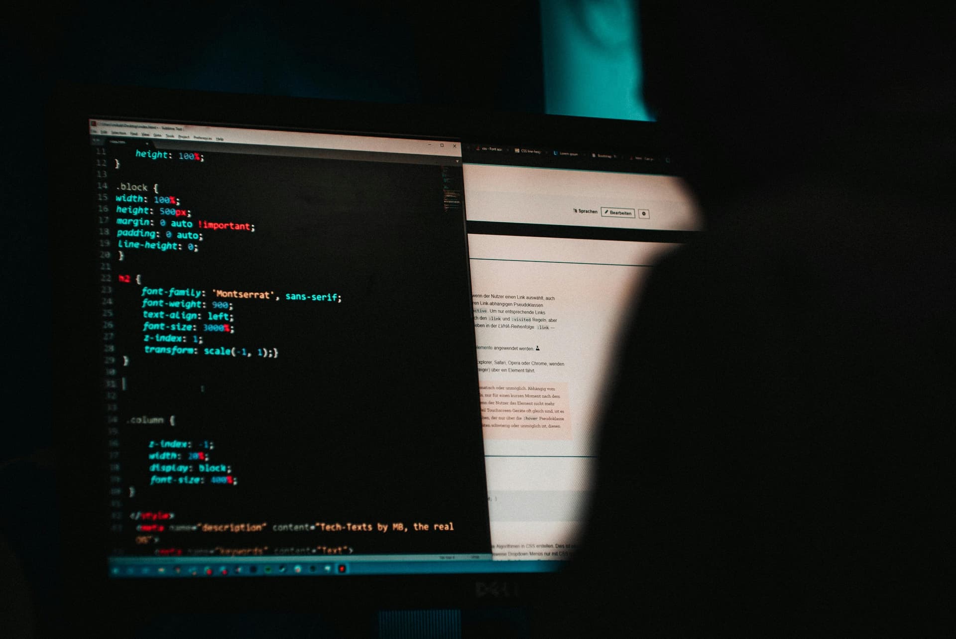 A computer monitor displays coding on the left side and a webpage on the right side, viewed by a person in a dimly lit room.