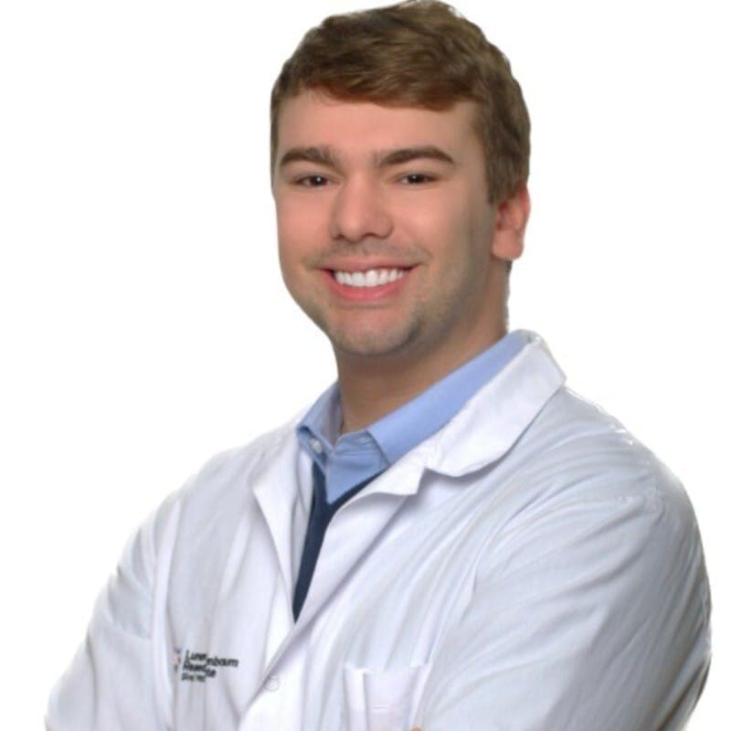 White guy wearing a white lab coat over a baby blue dress shirt.