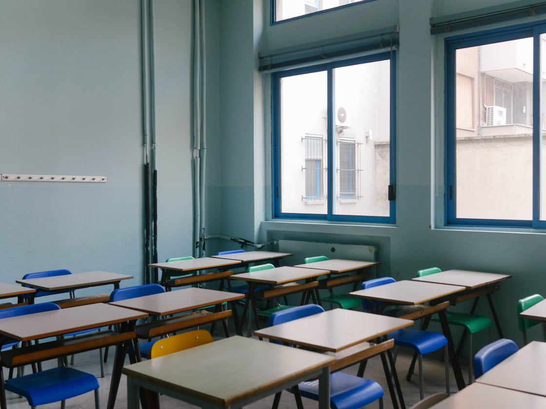 A classroom full of desks and blue and green chairs.