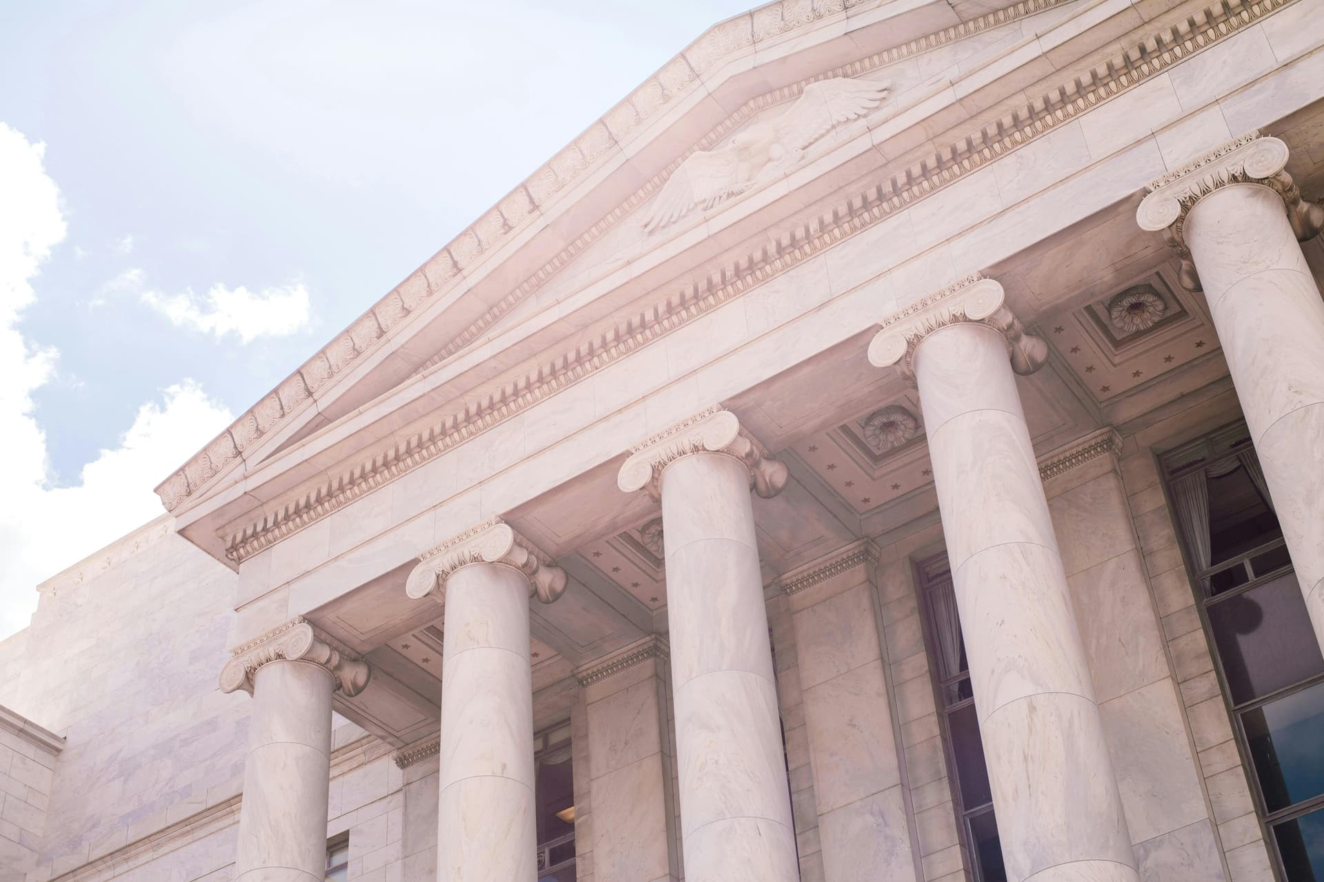 A close-up view of a classical government building with large marble columns and an engraved eagle at the top.